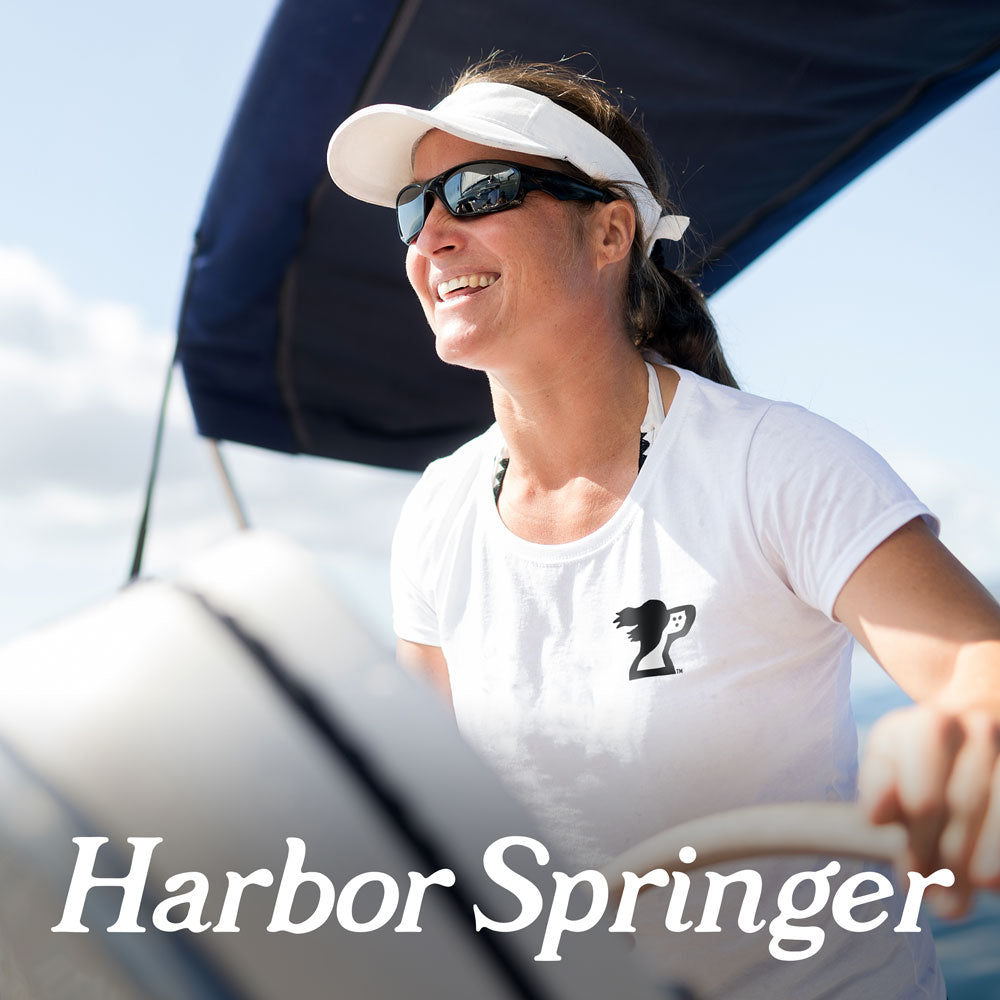 Harbor Springs Michigan inspired brand, Harbor Springer dog logo on a white womens t-shirt worn by a woman sailing.