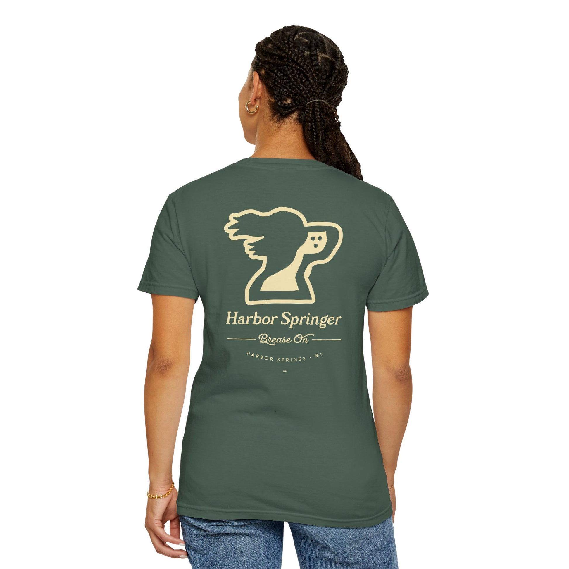 Standing woman with forest green t-shirt by the Harbor Springer brand with a springer spaniel dog logo and Brease On tagline on the back.