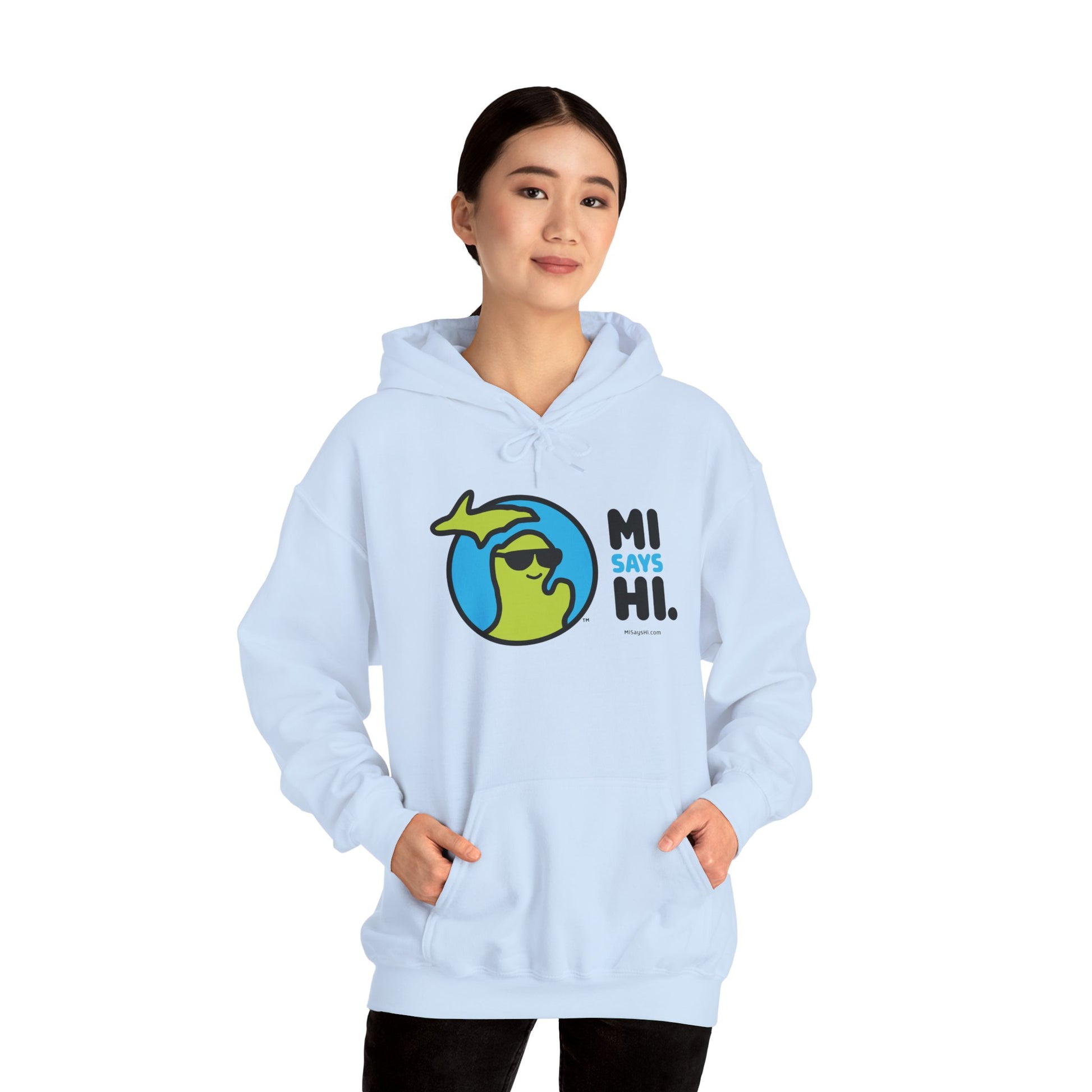 Woman wearing a light blue hoodie with waving Michigan logo wearing sunglasses and smiling for the MI Says Hi brand.